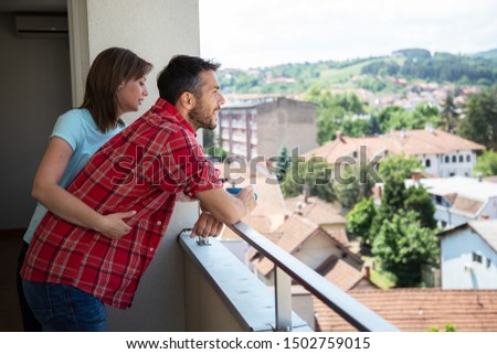 Young couple moving into new apartment, standing on terrace,stock photo