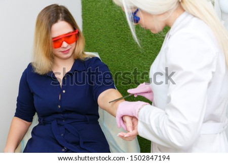 A young woman is preparing for laser hair removal. The girl in the blue dress in the salon hair removal laser