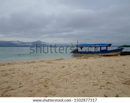 Small blue rustic boat on San Blas islands beach, turquoise water, Panama, mountain range in the background