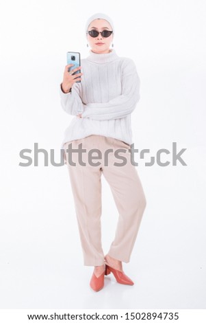 Beautiful asian muslim woman with white shirt and white hijab wearing sunglass while standing isolated on white background.Copy space.