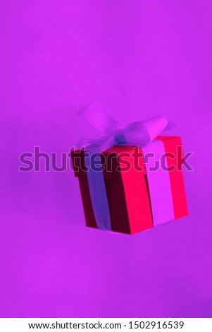 festive holiday card with red gift box levitating in neon light colors