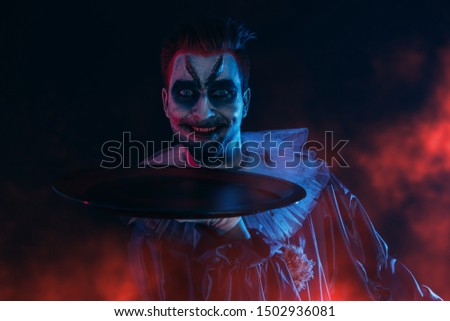 A portrait of an angry crazy clown from a horror film with a platter. Halloween, carnival.