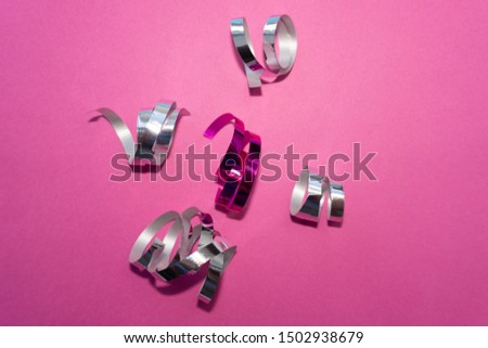 Festive tape, holiday ribbon, confetti on pink background.