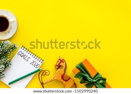 Planning New Year 2020. Notebook with goals on yellow background top view space for text