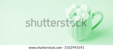 Trendy neo mint pastel background. Cup of dark coffee, hearts shaped marshmallow. Valentine's wedding day concept. Romantic girly femininy background

