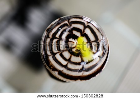 Bird's eye view of Iced coffee with cream and sauce in take away cup on table background