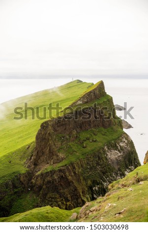 Mykinesholmur vertical picture with cliffs and nesting birds. Mykines, Faroe Islands.