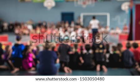 people blurred concept watching a show in a gym during the day