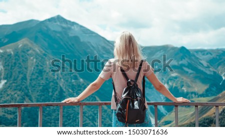 Woman hiking in mountains at sunny day time. View of Kazbegi, Georgia. Beautiful natural mountain background