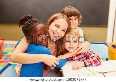 Young woman as a childminder or teacher hugs children in daycare or elementary school Royalty-Free Stock Photo #1503075977