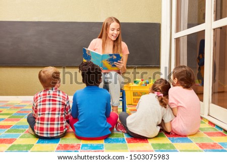 Teacher reads from a children's book in front of a daycare or daycare