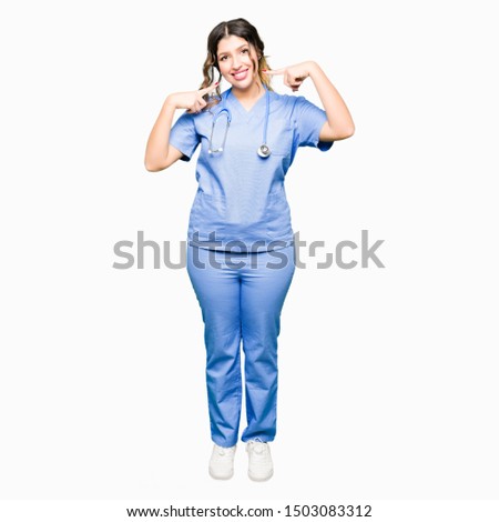 Young adult doctor woman wearing medical uniform smiling confident showing and pointing with fingers teeth and mouth. Health concept.