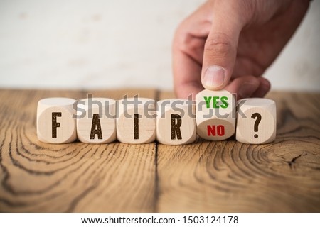 hand is moving one cube with options yes and no deciding between fair and unfair Royalty-Free Stock Photo #1503124178