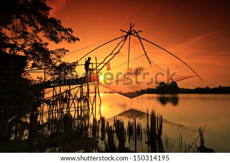 A Silhouette Fisherman Catching Fish From square dip net at Pak Pra Canal Phatthalung Province , Thailand.