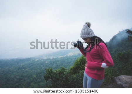 Asian women go hiking in the winter,Tourist woman taking with camera travel picture, enjoying mountains landscape,Travel take photo, tourist,Hipster young girl is shooting photo