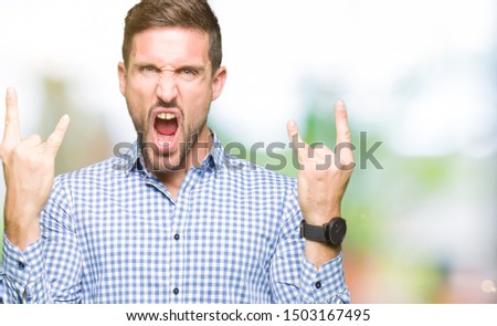 Handsome business man with blue eyes shouting with crazy expression doing rock symbol with hands up. Music star. Heavy concept.
