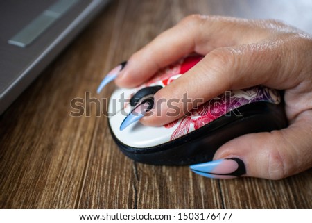Females hand with manicured nails holds computers mouse