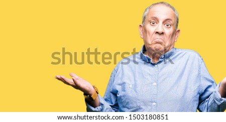 Handsome senior businesss man wearing elegant shirt clueless and confused expression with arms and hands raised. Doubt concept. Royalty-Free Stock Photo #1503180851