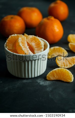 selective focus, still life, peeled tangerine slices in a white Cup, with fruit in the background, on a dark background, low key