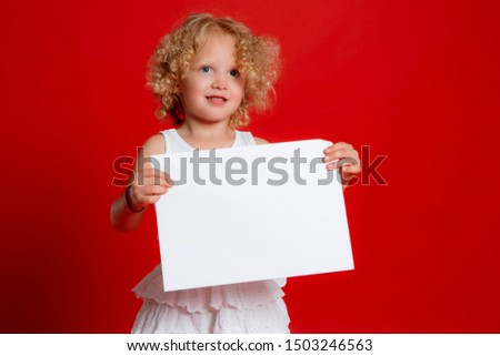 Cute little girl isolated on red holding blank paper