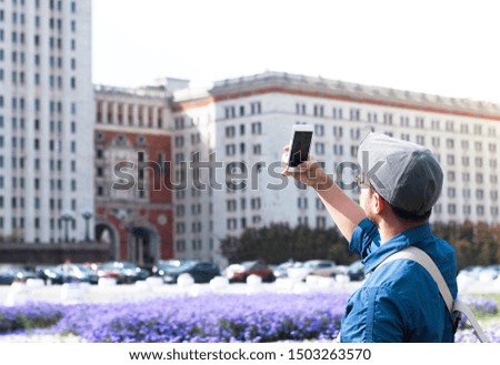 Travel concept - travel photos. A man from the back with a smartphone in his hand, portrait. A person takes a photograph on her mobile phone a Sight of Russia, architecture. outdoors or outside