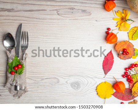 Seasonal table setting with pumpki, festive Thanksgiving with cutlery and red berries