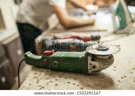 a man produces furniture in the background in front of a circular saw