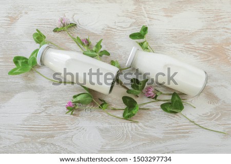 milk bottles and clover on a light wooden background