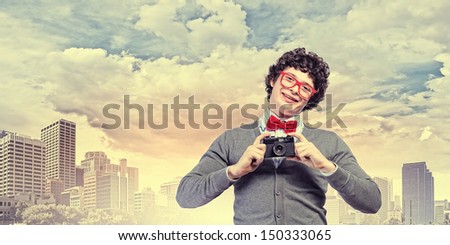 Image of young man in red tie with photo camera taking pictures