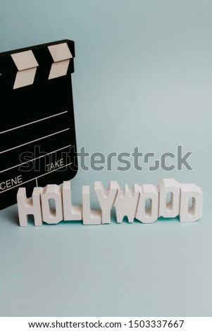 Hollywood wooden words and a Clapboard in a pastel turquoise background. Movie Concept