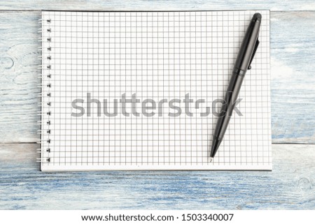black pen and paper notebook with space for text on a light blue old wooden background. top view. flat lay