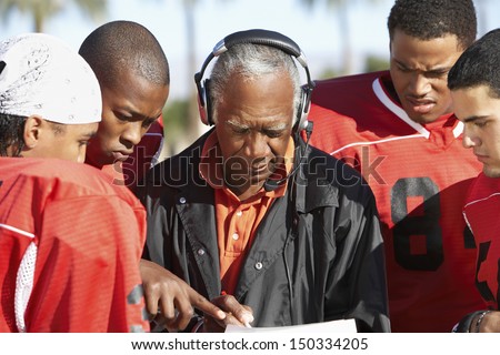 Football players and coach discussing strategy together Royalty-Free Stock Photo #150334205