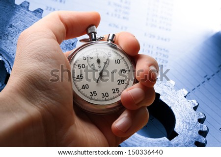 Hand holding stopwatch, budget and two mechanical ratchets