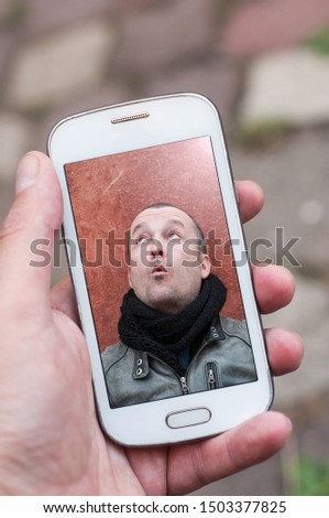 Closeup of man taking a selfie with is smartphne in his hand in the street