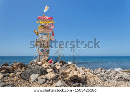 Signpost with stones at beach with sea of Bonaire