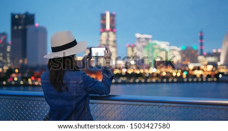 Woman take photo on cellphone in city of Yokohama ct night
