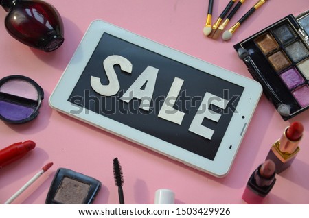 Different types of decorative cosmetics, next to a tablet with the words sale. Online Shopping Concept. Overhead view of Tablet and essential beauty items, Top view of female fashion accessories