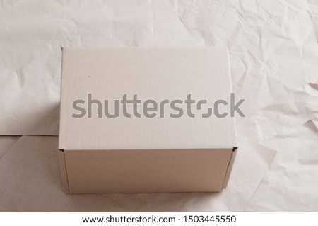 Closed carton box laying on sheets of crumpled kraft paper.