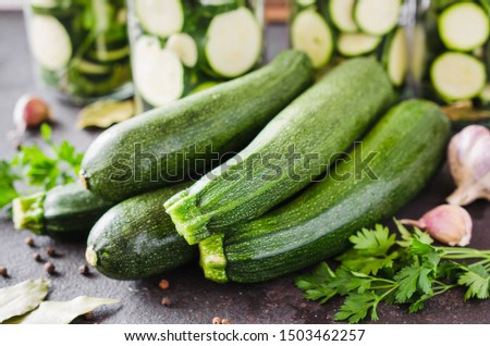 Fresh organic zucchini, garlic and parsley, herbs and spices. Process of home conservation of zucchini in jars Royalty-Free Stock Photo #1503462257