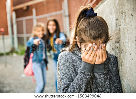 A sad girl intimidation moment on the elementary Age Bullying in Schoolyard Royalty-Free Stock Photo #1503499046