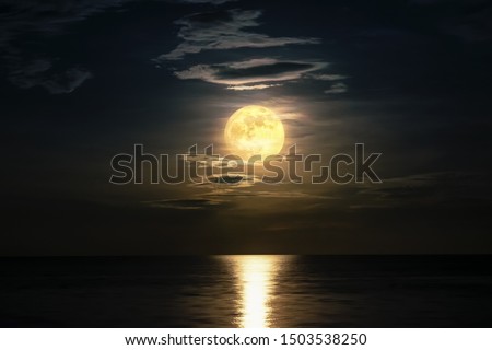 Super full moon cloudy in dark sky on the ocean horizon at midnight, Moonlight yellow gold reflects the wave water surface, Beautiful fantasy nature landscape view the sea at night scene background Royalty-Free Stock Photo #1503538250
