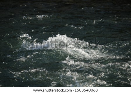 Closeup of fast flowing stream. Bubbles and foam on water surface,
