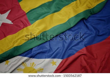waving colorful flag of philippines and national flag of togo. macro