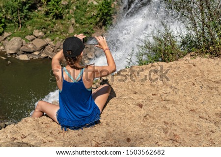 Young Woman Taking Photograph Of Waterfall With Mobile Phone At Burgess Falls State Park In Tennessee