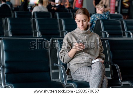 Young girl at the airport waiting for her departure. Scrolling smartphone
