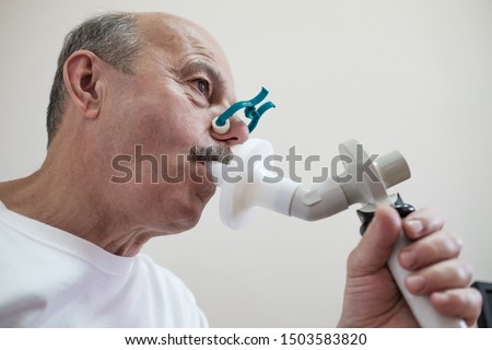 Senior hispanic man man testing breathing function by spirometry. Diagnosis of respiratory function in pulmonary disease Royalty-Free Stock Photo #1503583820