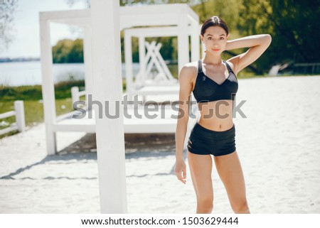 Pretty lady on a summer beach. Sport girl in a black swimsuit