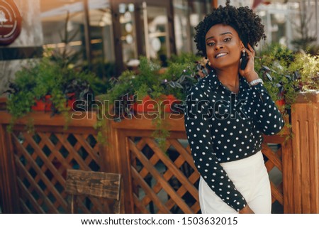 A young and stylish dark-skinned girl standing in a sunny city