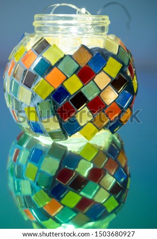 The colorful mosaic glass bottle, reflecting on the board.