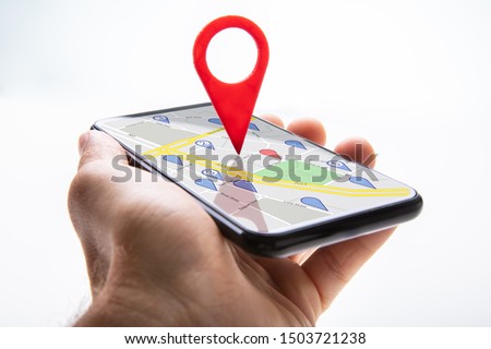 Close-up Of A Person's Hand Holding Cellphone With Red Map Pin Pointer Against White Background Royalty-Free Stock Photo #1503721238